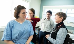 SMP student Kara Ruff examines a volunteer patient alongside Dr. Marjorie Docherty, Family Practice Lead for SMP, and SMP classmate Dylan Nemes.